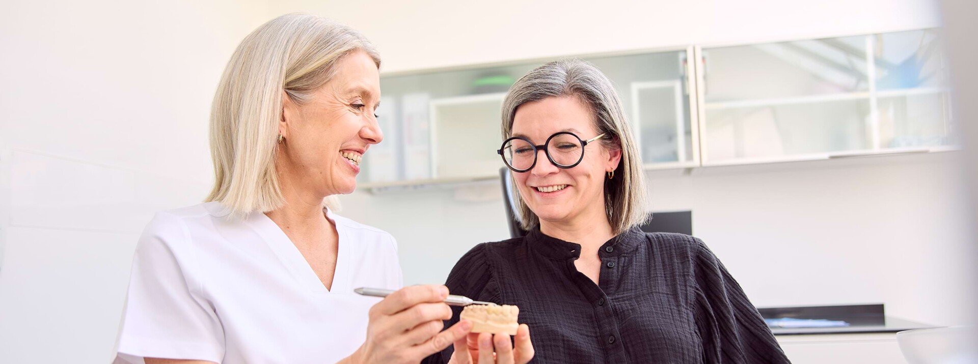 Dr. Silvia Hahn erklärt einer Patientin etwas am Behandlungsstuhl