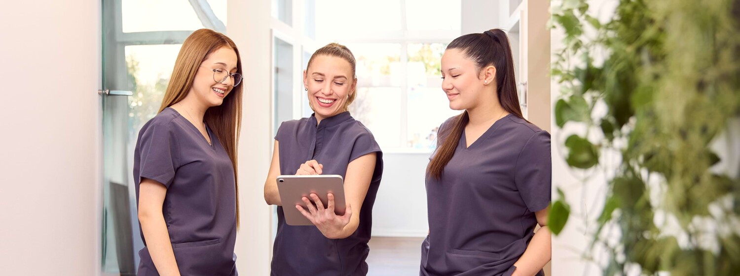 3 Teammitglieder stehen im Flur und besprechen sich mit einem Tablet