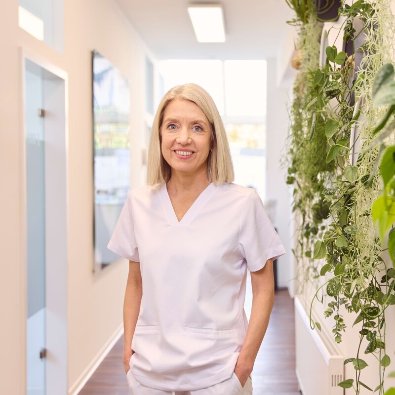 Dr. Silvia steht im Flur und lächelt