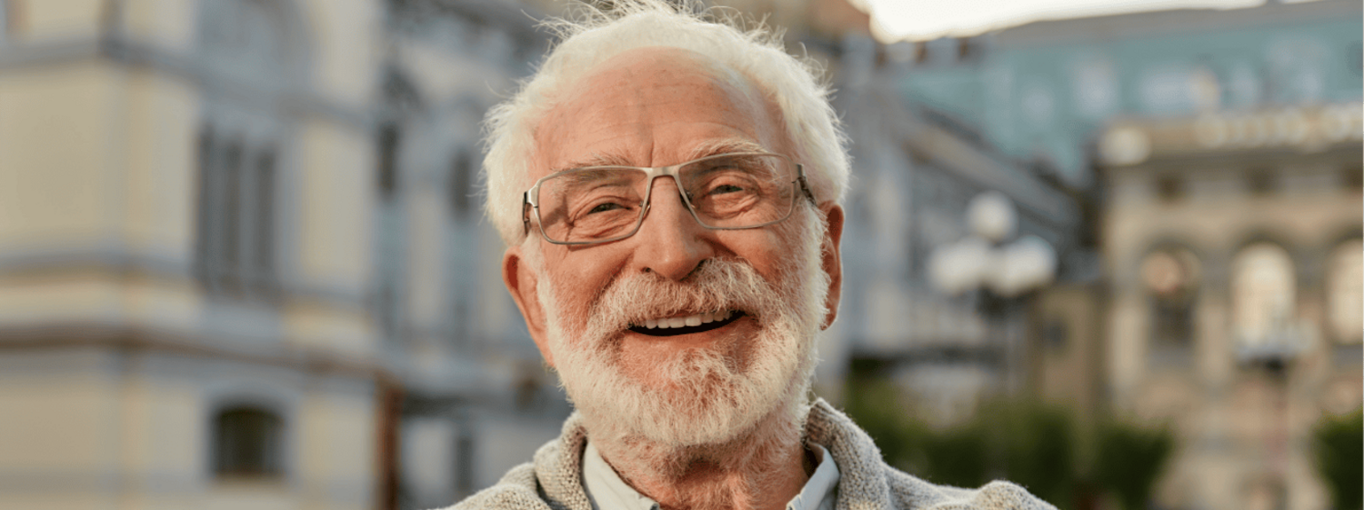 Senior steht draußen vor einem Gebäude und lächelt
